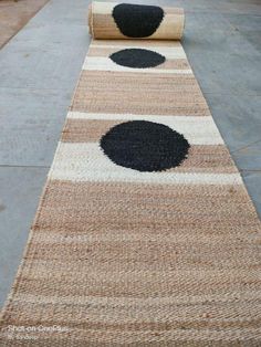 an area rug with black and white circles on the ground next to a roll of jute