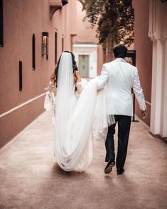 a bride and groom walking down an alley