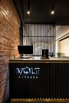 the front desk of volt fitness is lit up with neon lights and black bars