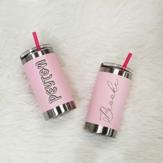 two pink tumblers sitting on top of a white fur covered floor next to each other