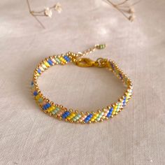 a gold bracelet with multicolored glass beads on a white cloth covered tablecloth