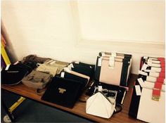 a table topped with lots of different types of purses and books on top of it