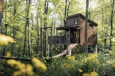 a small wooden cabin in the woods with stairs leading up to it's second floor