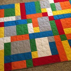 a close up of a quilt on the floor with different colored squares and circles in it