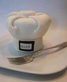 a white plate topped with a cake covered in icing next to a fork and knife