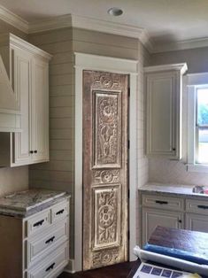 an old door in the middle of a kitchen with white cabinets and marble counter tops