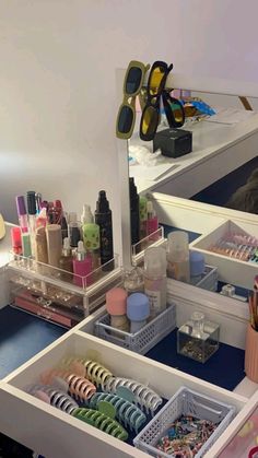 an organized makeup drawer with various items in it and a large mirror above the drawers