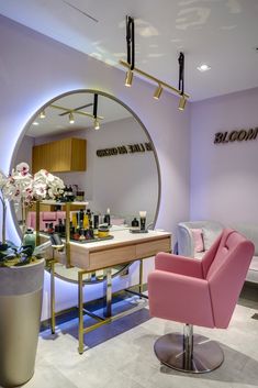 a pink chair sitting in front of a mirror on top of a counter next to a plant