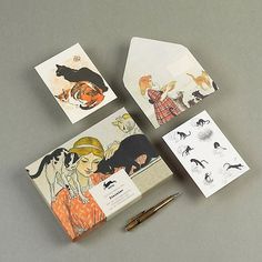 four postcards with pictures of cats on them and a pen sitting next to it