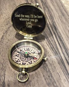 a compass sitting on top of a wooden table next to a quote written in it