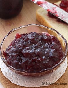 a glass bowl filled with cranberry sauce on top of a wooden cutting board