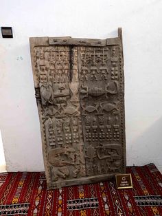 an old door with carvings on it and a plaque next to it in front of a white wall