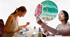 two women are sitting at a table and one is holding up a clock with the ocean on it