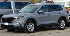 the front end of a silver honda pilot parked in a parking lot next to other cars