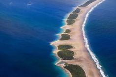 an island in the middle of the ocean surrounded by blue water and sand, as seen from above