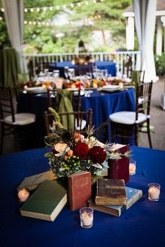 a table topped with books and flowers on top of a blue cloth covered tablecloth