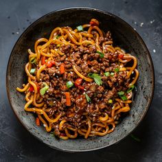 a bowl filled with noodles and meat on top of a table