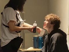 a man with long hair is shaving another mans face