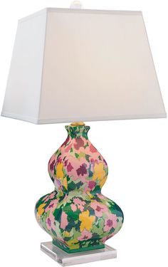 a lamp that is sitting on top of a glass base with a flowered vase underneath it