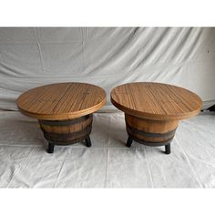 two wooden barrel tables sitting next to each other on top of a white cloth covered floor