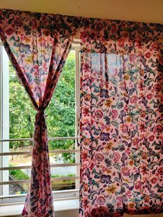 an open window with pink curtains in front of it and trees outside the window sill