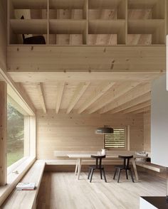 the interior of a house with wooden walls and flooring, including benches and tables