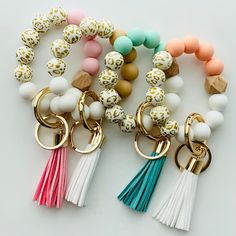 several different colored beads and tassels on a white surface with gold accents,