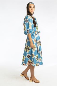 a woman in a blue and white dress standing with her hand on her hippie