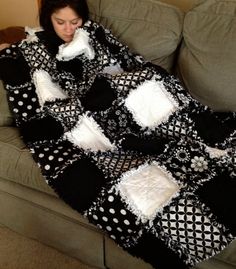 a woman is sitting on a couch under a black and white blanket with polka dots