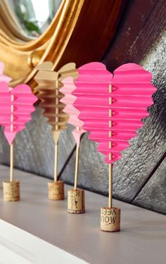 pink heart shaped paper lanterns are lined up on a shelf