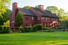 a large red house sitting on top of a lush green field