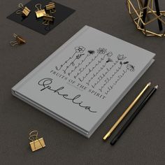 an open notebook with writing on it next to some gold objects