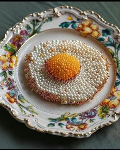 an egg is sitting on top of a plate with pearls in the shape of flowers