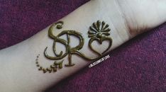 a person with a tattoo on their arm that has the letter r and is decorated in gold