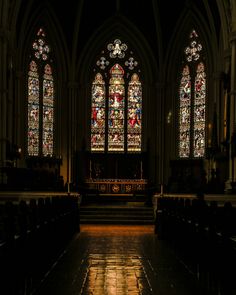 an empty church with stained glass windows and pews in the foreground, at night