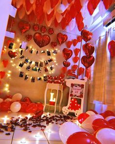 a room filled with lots of red balloons and hearts hanging from the ceiling above it