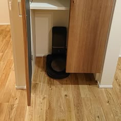 a black toilet sitting in the corner of a room next to a wooden cabinet and counter