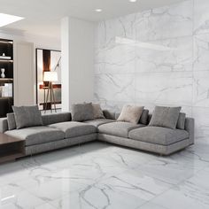 a modern living room with marble flooring and white walls, along with a large sectional sofa