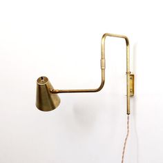 a wall mounted light with a cord attached to the back of it's arm