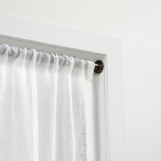 a white curtain hanging on the side of a door with a brown handle and black hardware