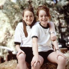 two young women sitting on top of hay bales