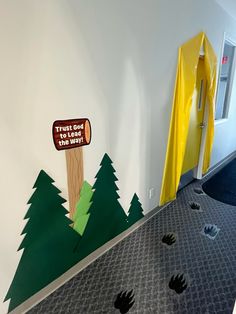 an office hallway decorated with paper cutouts and trees on the floor next to a door