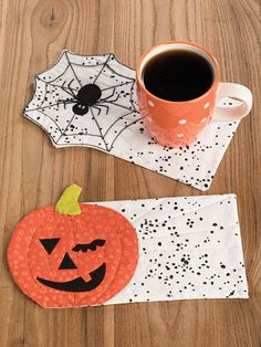 a cup of coffee sitting on top of a wooden table next to a paper pumpkin