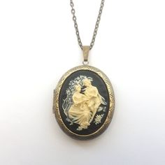 Classical style Victorian inspired large cameo locket necklace in black and cream. The detailed cameo has a black background, and is set on a large opening locket in gunmetal or antiqued bronze plated on a matching chain. The locket will hold two photos (approx the same size as the cameo), or any small precious object.  The locket measures just under 2 inches (50mm) from top to bottom, and the matching chain is has a lobster clasp. The chain length can be altered at no extra cost. Choose gunmeta Antique Gold Cameo Medallion Locket Necklace, Vintage Black Locket Necklace, Vintage Collection Cameo Medallion Locket Necklace, Vintage Medallion Cameo Locket Necklace, Black Cameo Medallion Jewelry, Vintage Collection Medallion Cameo Locket Necklace, Elegant Black Medallion Locket Necklace, Victorian Cameo Locket Necklace As A Gift, Vintage Black Cameo Necklace