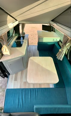 the interior of a camper with blue couches and white tables in it's center