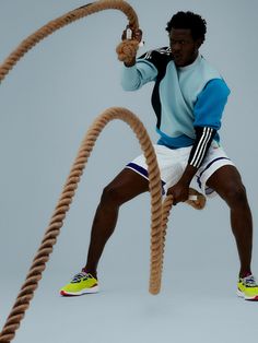 a man in blue and white shirt holding a rope while standing on top of a pair of shoes