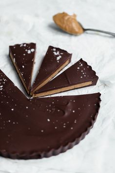 there are pieces of chocolate tart on the table with spoons and utensils