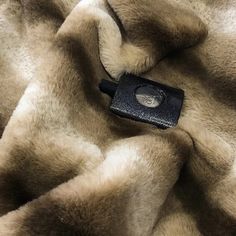 a cell phone laying on top of a fur covered blanket