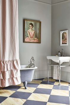 a bathroom with a checkered floor, tub and painting on the wall above it