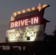 the drive - in sign is lit up at night with lights on it's sides